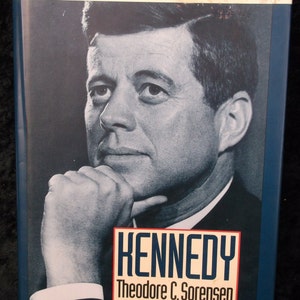 May include: A blue book cover with the title "Leaders of Our Time" and a black and white photo of John F. Kennedy. The book's title is "Kennedy" by Theodore C. Sorensen.