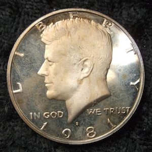May include: Silver half dollar coin featuring a profile of John F. Kennedy with the inscription "In God We Trust" and the year "1968".