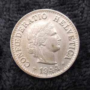 May include: Silver Swiss coin with the inscription "CONFOEDERATIO HELVETICA" and the year "1944". The coin features a portrait of a woman with a crown.