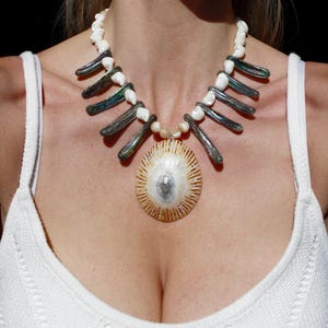 May include: A white and iridescent shell necklace with a large, round, brown and white shell pendant.