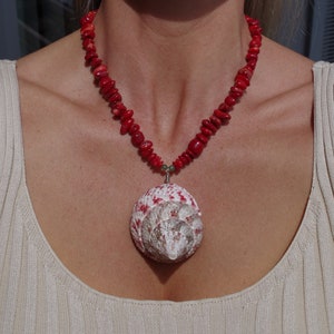 May include: A red coral necklace with a large white and red seashell pendant.