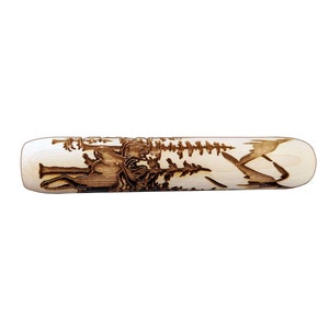 May include: A wooden rolling pin with a carved design of a moose and trees. The rolling pin is light brown and the carving is dark brown.