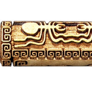 May include: A carved wooden cylinder with intricate relief patterns. The design features stylized figures, wavy lines, and geometric shapes, all in a warm, natural wood tone. The ends have repeating square patterns.
