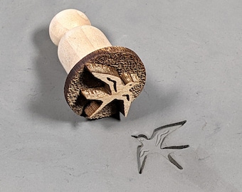 May include: A wooden stamp with a bird design. The stamp is used to create impressions in clay or dough.