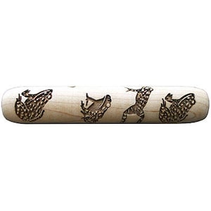May include: A wooden rolling pin with a design of four frogs in various poses. The frogs are burned into the wood, creating a dark brown contrast against the light wood.