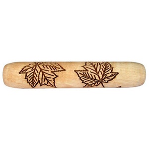 May include: A light-coloured wooden rolling pin featuring etched maple leaf designs. The cylindrical pin has rounded ends. The leaves are detailed with visible veins, adding a naturalistic touch to the kitchen tool, ideal for baking.