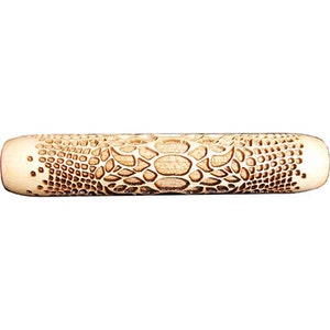 May include: A light-coloured wooden rolling pin featuring a detailed, textured pattern resembling reptile skin. The rolling pin is cylindrical with rounded ends, and the surface is etched with a repeating scale-like design. The overall appearance is natural and rustic.