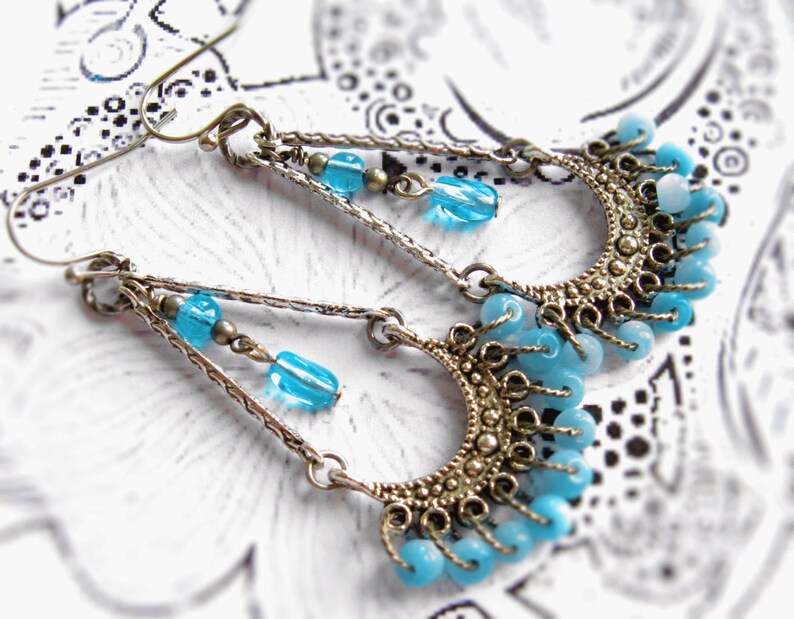May include: A pair of silver dangle earrings with blue glass beads and a crescent moon design.