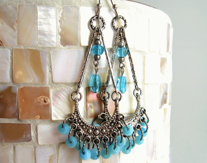 May include: Silver dangle earrings with a crescent moon design and blue glass beads.