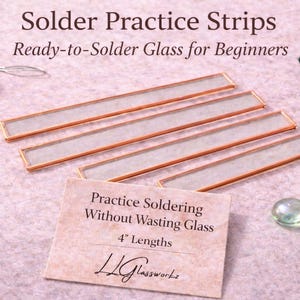 May include: Four rectangular glass strips with copper foil edges for soldering practice. Includes a spool of solder, a soldering tool, and two glass cabochons. Text reads: Solder Practice Strips, Ready-to-Solder Glass for Beginners, Practice Soldering Without Wasting Glass, 4" Lengths, LLGlassworkz.