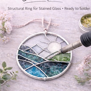 May include: A circular stained glass frame with a landscape design, featuring mountains, a sun, and water in shades of blue and green. The frame is ready to solder and is labeled "Circle Frame". The text "12 Gauge Pre-Tinned" is also visible.