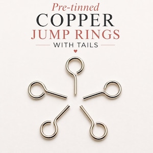 May include: Five pre-tinned copper jump rings with tails arranged in a circular pattern. The text above reads Pre-tinned COPPER JUMP RINGS WITH TAILS with a small heart icon. The jump rings are metallic silver in color with a circular loop and a straight tail.