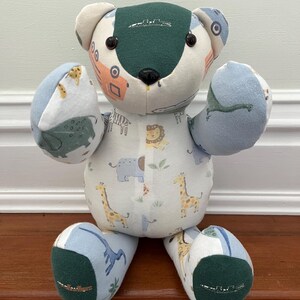May include: A patchwork teddy bear with a green head and feet. The arms and legs are blue and white animal print fabric. The body is white with a repeating pattern of giraffes, lions, and elephants. The bear is handmade.