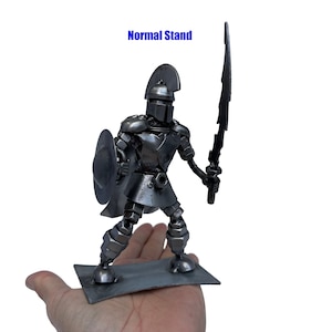 May include: A metal sculpture of a warrior holding a sword and shield. The warrior is standing on a metal base. "Normal Stand" is written in blue text above the sculpture.