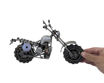 May include: A silver motorcycle sculpture made from recycled metal parts. The motorcycle has a detailed engine and wheels made from chains.