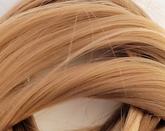 May include: A close-up of a bundle of light brown human hair extensions. The hair is smooth and silky, with a natural shine.