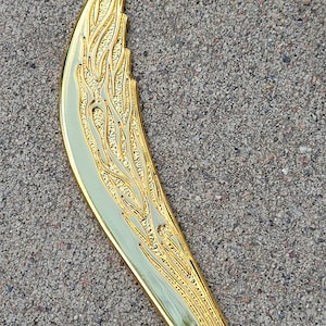 May include: A gold-colored, decorative knife with a curved blade and an intricate, floral design.