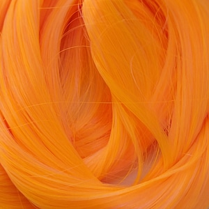 May include: A close-up of a bright orange synthetic hair extension. The hair is soft and silky, and it is arranged in a loose, flowing style.