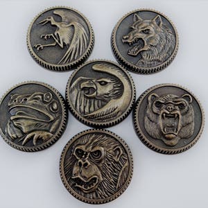 May include: Six antique bronze-colored medallions with detailed animal designs: a crane, wolf, eagle, frog, bear, and monkey. Each medallion has a textured border and is arranged in a circular pattern against a white background.