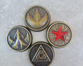 Könnte beinhalten: Vier antike, kreisförmige Münzen mit detaillierten Designs. Eine Münze zeigt einen roten Stern, eine andere ein Dreieck, und die anderen haben komplizierte Symbole. Die Münzen haben eine Bronze-Oberfläche und einen strukturierten Rand.