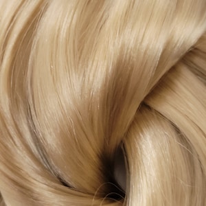May include: Close-up of a bundle of light blonde human hair extensions. The hair is smooth and silky, with a slight sheen.