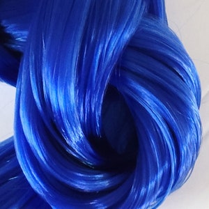 May include: A close-up of a bundle of bright blue yarn. The yarn is soft and fluffy, and it is perfect for knitting or crocheting.