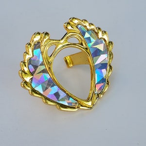 May include: A gold heart-shaped frame with an iridescent finish. The frame has a delicate, ornate design and is perfect for displaying a small photo or other keepsake.