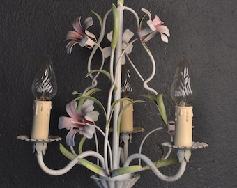 May include: A white metal chandelier with a floral design. The chandelier has three lights and is decorated with pink and green flowers.