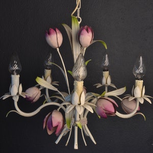 Pu&ograve; includere: Lampadario in metallo bianco con accenti di fiori rosa e lampadine in vetro trasparente. Il lampadario ha una catena e una cupola in metallo bianco.