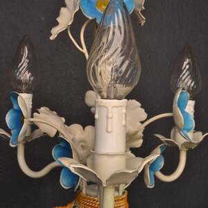 May include: White metal chandelier with blue and white flowers and three clear glass bulbs. The chandelier has a rope detail around the base.