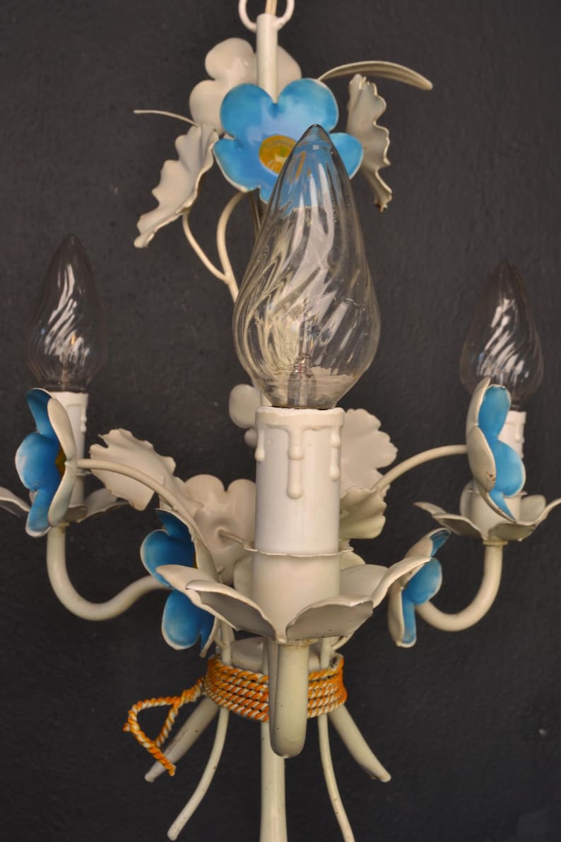 May include: White metal chandelier with blue and white flowers and three clear glass bulbs. The chandelier has a rope detail around the base.