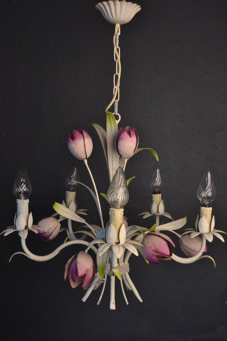 Pu&ograve; includere: Lampadario in metallo bianco con accenti di fiori rosa e lampadine in vetro trasparente. Il lampadario ha una catena e una cupola in metallo bianco.