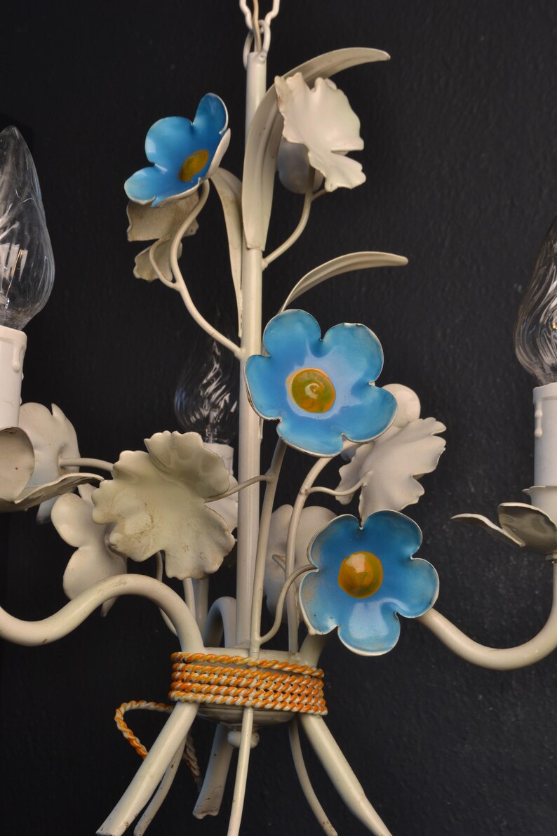 May include: White metal chandelier with blue flowers and leaves. The chandelier has a rope detail around the base.