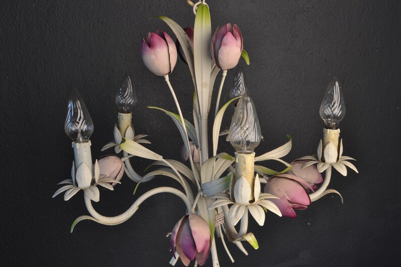 Pu&ograve; includere: Lampadario in metallo bianco con paralumi a forma di tulipano rosa e lampadine in vetro trasparente. Il lampadario ha un design floreale con foglie e steli.