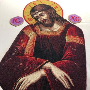 May include: Embroidered icon of Jesus Christ wearing a red robe with a gold halo. The icon is surrounded by two smaller embroidered patches, one with the letters "IC" and the other with the letters "XC".