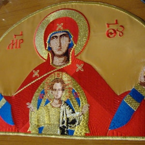 May include: Embroidered icon of the Virgin Mary and Child, with a gold background and red and blue accents. The icon is framed in gold and has the text "MP OY" in red.