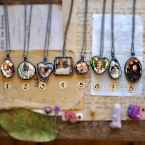 May include: Eight silver necklaces with glass pendants featuring different photos. Each pendant is numbered 1 through 8.