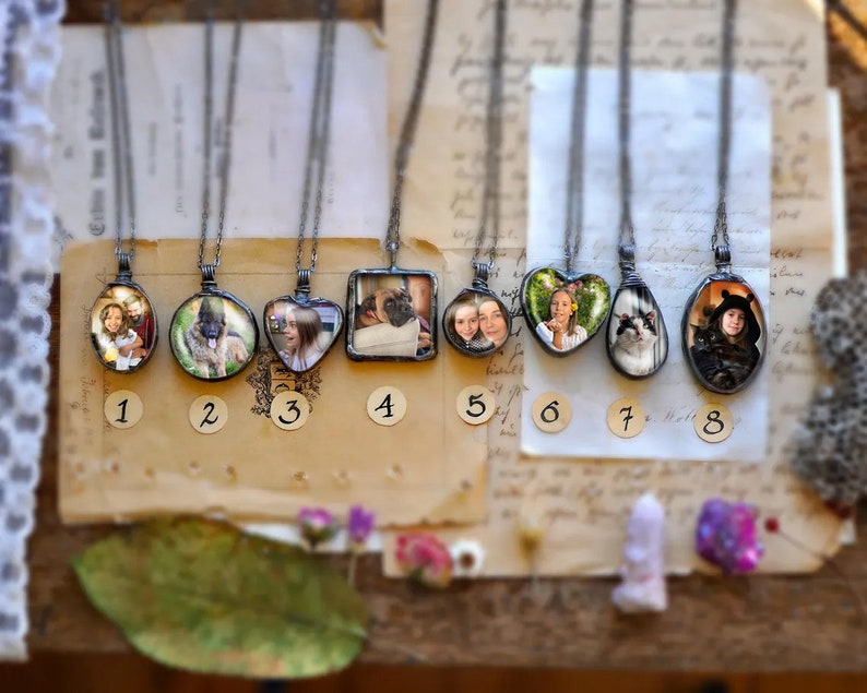 May include: Eight silver necklaces with glass pendants featuring different photos. Each pendant is numbered 1 through 8.