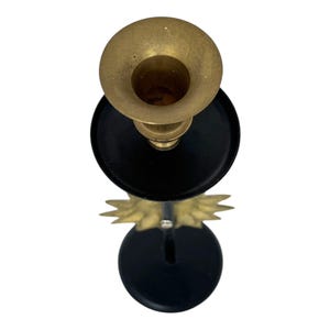Peut inclure: Un bougeoir en laiton avec une base et des accents noirs. Le haut du support est en forme de coupe en laiton, et la base a un design d&eacute;coratif de couleur or. Le bougeoir est con&ccedil;u pour contenir une seule bougie.