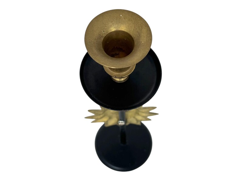Peut inclure: Un bougeoir en laiton avec une base et des accents noirs. Le haut du support est en forme de coupe en laiton, et la base a un design d&eacute;coratif de couleur or. Le bougeoir est con&ccedil;u pour contenir une seule bougie.