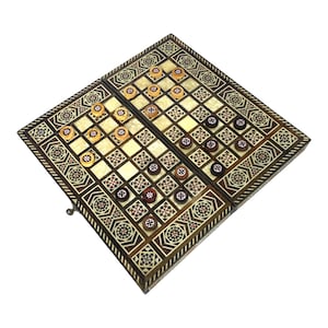May include: A wooden backgammon game set with an intricate inlaid design. The board is open and the pieces are arranged on the board. The board is made of dark wood with a light wood inlay.