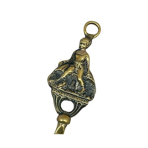 May include: A brass doorstop featuring a figure of a man standing on a mushroom with the text "Polperro Pisk" inscribed on the base.