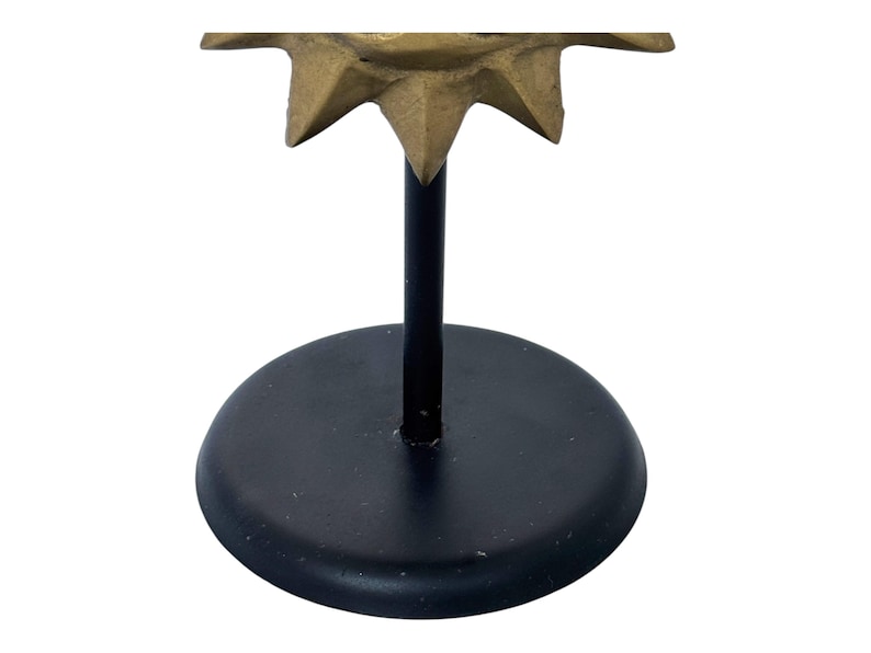 Peut inclure: Un bougeoir d&eacute;coratif avec une base et une tige noires, surmont&eacute; d'un motif en forme d'&eacute;toile de couleur or. La base est ronde et la tige est une fine tige droite. Le dessus en forme d'&eacute;toile a plusieurs pointes.