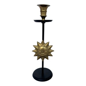 Peut inclure: Un bougeoir en laiton avec une base et une tige noires. Le bougeoir pr&eacute;sente un motif de soleil avec un visage souriant. Le bougeoir mesure environ 30 cm de haut.