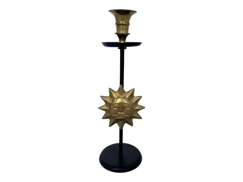 Peut inclure: Un bougeoir en laiton avec une base et une tige noires. Le bougeoir pr&eacute;sente un motif de soleil avec un visage souriant. Le bougeoir mesure environ 30 cm de haut.