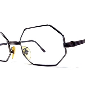 May include: Black metal frame eyeglasses with octagonal lenses. The glasses have a simple, minimalist design.
