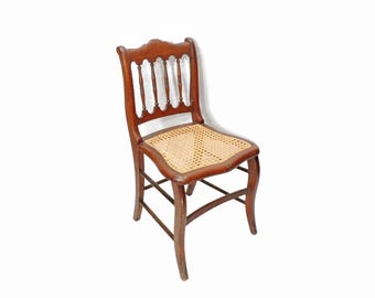 Silla auxiliar rústica vintage antigua con asiento de caña tejida y estructura de madera de caoba.