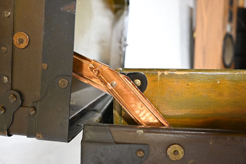 May include: A vintage metal suitcase with a copper hinge. The suitcase is open and the inside is lined with wood.