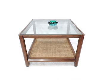 Mesa de centro de estilo modernista vintage con estante de caña tejida y tapa de cristal.