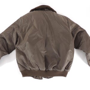 May include: A brown bomber jacket with a faux fur collar. The jacket has a ribbed hem and cuffs, and a quilted design on the back. The jacket is made of a smooth, shiny material.